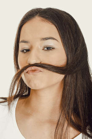 Teen woman putting hair like moustache.の写真素材