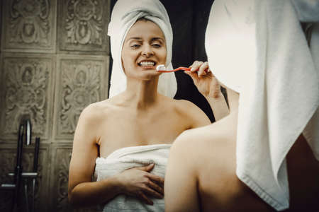 Woman brushing teeth in bathroom.の写真素材