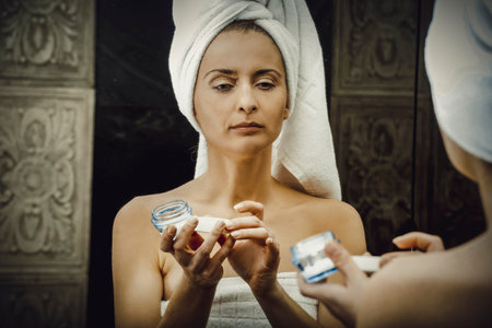 Woman putting anti-aging cream on her face.