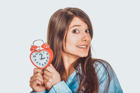 Young woman in big shirt holding alarm clock.の写真素材