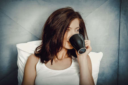 Woman drinking coffee in bed.の写真素材