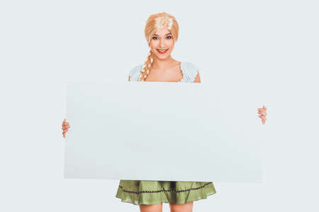 Woman wearing Bavarian dress holding empty banner.の写真素材