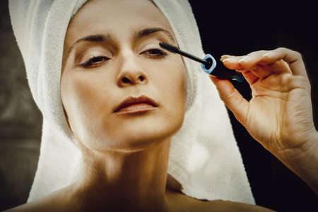 Woman makes light day makeup in bathroom.の写真素材