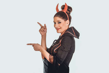 Woman in devil carnival costume pointing aside.の写真素材
