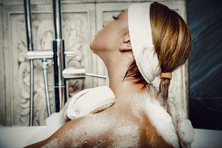 Bathing woman cleaning her back with soap.の写真素材