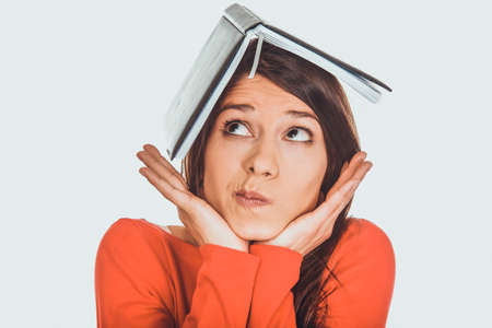 Thoughtful student woman with her note on head.の写真素材