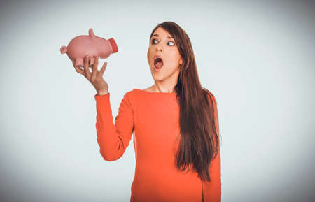 Shocked young woman with piggybank.の写真素材