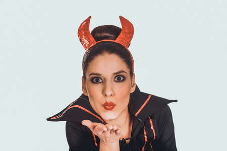Woman in devil costume blowing a kiss.の写真素材