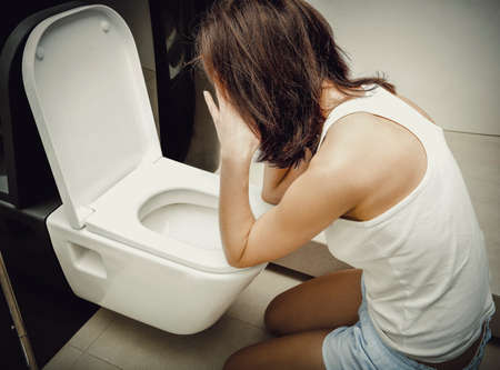 Woman vomiting in toilet.の写真素材