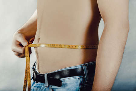 Young man measuring waist.の写真素材