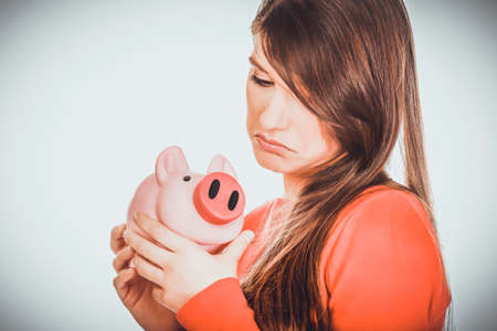 Worried young woman with piggybank.の写真素材