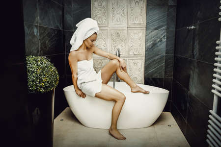 Beautiful woman sitting on bathtub.の写真素材