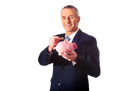 Cheerful businessman holding piggybank