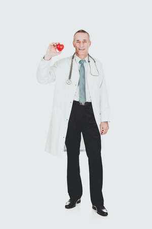 Mature male doctor holding heart modelの写真素材