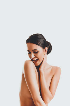 Topless woman sitting on desk, touching her neckの写真素材