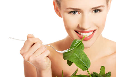 Portrait of nude woman eating lettuce from bowlの写真素材