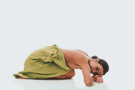 Woman curled up wrapped in towelの写真素材