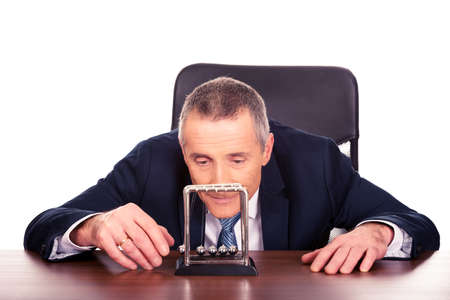 Businessman in office playing with newton ballsの写真素材