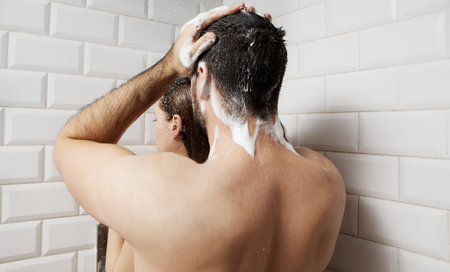Young couple washing their heads in the showerの写真素材