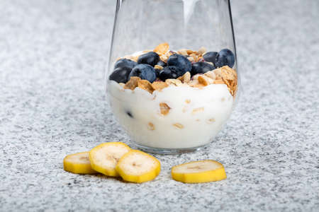 Dietetic breakfast - yoghurt with mueasli and huckleberries and bananaの写真素材