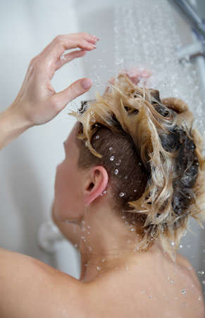 Beautiful naked woman washing her hair while taking shower in bathroom.の写真素材