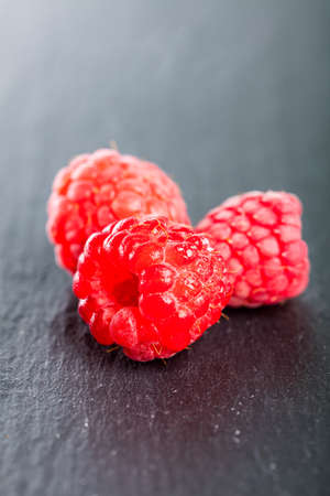 Three fresh juicy wet raspberries.の写真素材