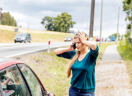 Woman dialing her phone after car crashの写真素材