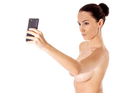 Nude beautiful woman taking selfie on white background.の写真素材
