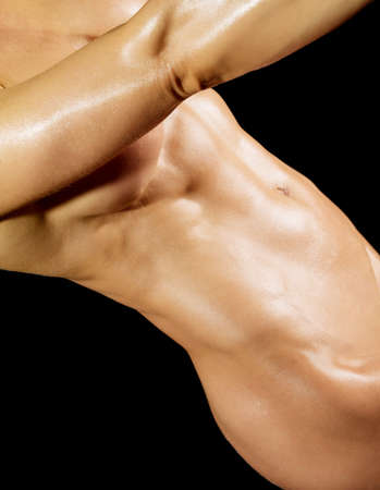 Muscular naked bodybuilder woman showing her muscles over black background.の写真素材