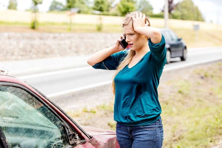 Woman dialing her phone after car crashの写真素材