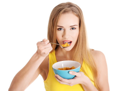 Beautiful caucasian slim woman eating corn flakes.