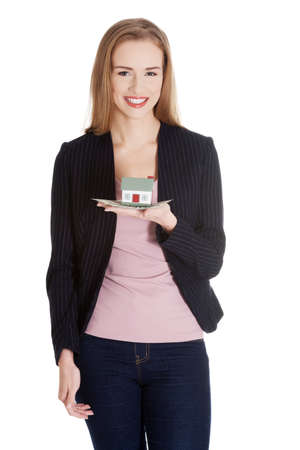 Beautiful casual caucasian business woman holding house model on her palm.の写真素材