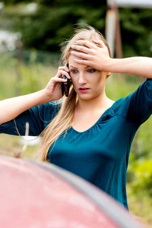 Woman dialing her phone after car crashの写真素材