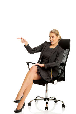 Businesswoman sitting on a chair and showing empty spaceの写真素材
