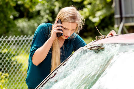Woman dialing her phone after car crashの写真素材