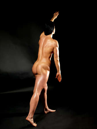 Muscular naked bodybuilder woman showing her muscles over black background.の写真素材