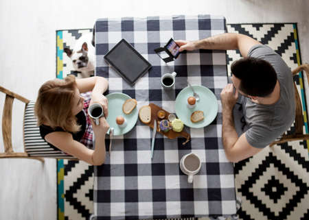 Loving couple sitting at a kitchen table, having a breakfast togetherの写真素材
