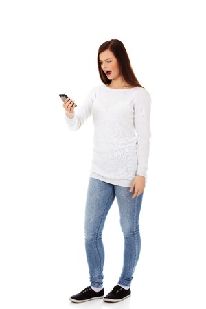 Young student woman yelling to the mobile phoneの写真素材