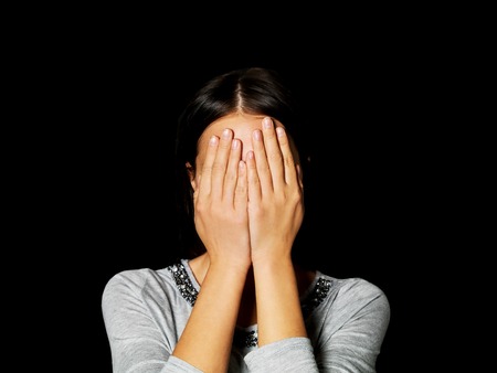 Young woman covering her face with her handsの写真素材