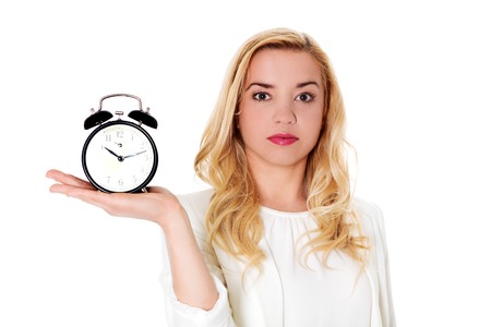 Blond woman showing alarm clock, isolated on white.の写真素材