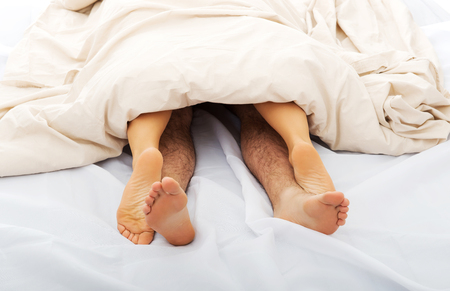Couples feet in bed.の写真素材