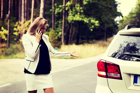 Young woman with broken car calling for helpの写真素材
