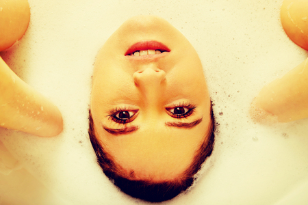 Young woman washing hair in bathの写真素材