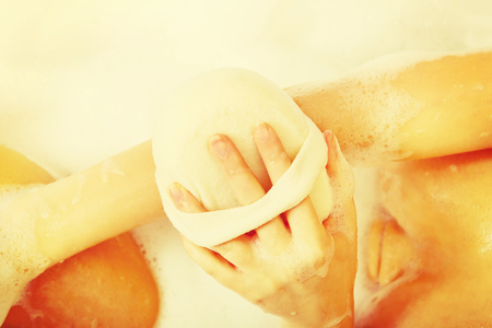 Woman washing herself by spongeの写真素材