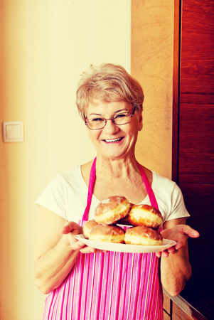 Senior woman holding plate with donutsの写真素材
