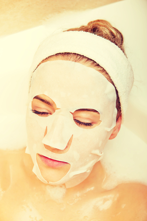 Woman sitting in bath with face maskの写真素材