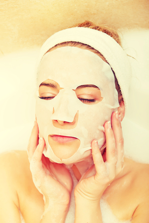 Woman sitting in bath with face maskの写真素材