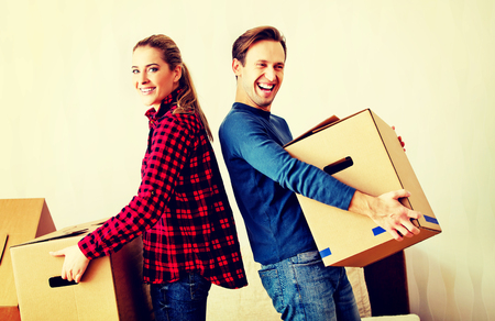 Happy couple carrying cardboard boxes in new homeの写真素材