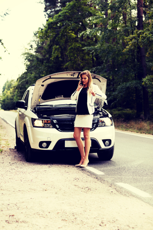 Young woman with broken car calling for helpの写真素材