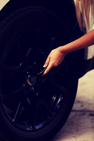 Woman is changing tire of car with wheel wrenchの写真素材
